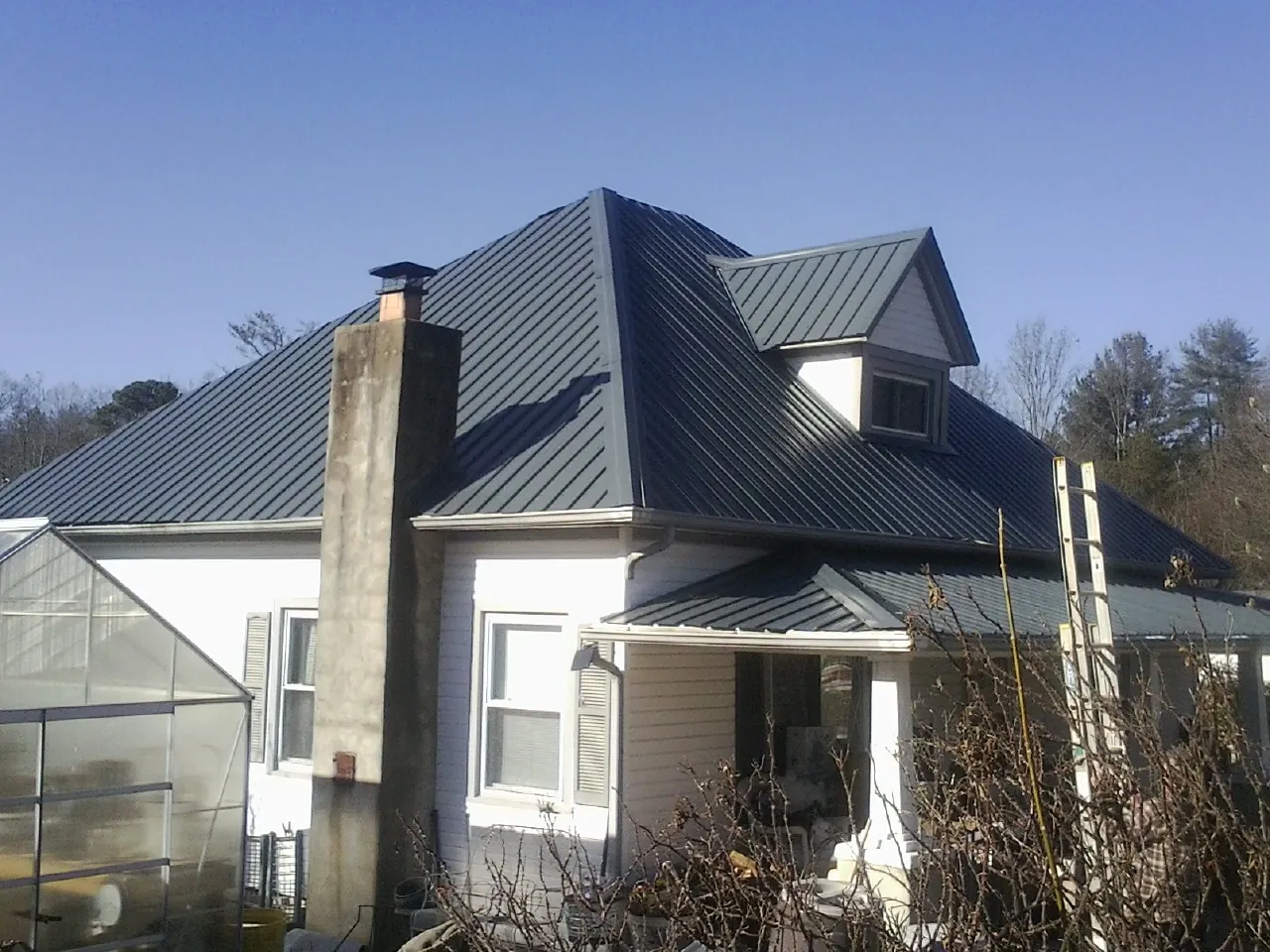 Dark blue standing seam metal roof on a white farmhouse with dormer — Slate & Tile Roof Repair by Roofing Brothers in Veneta
