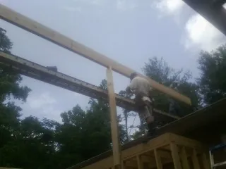 Carpenter setting a ridge beam over a new addition frame — Ice Dam Removal by Roofing Brothers in Veneta