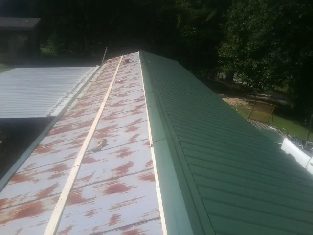 Old rusted panels beside newly installed green metal roofing — Wind Damage Roof Repair by Roofing Brothers in Veneta