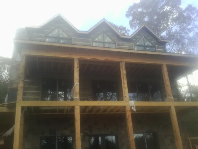 Dormers and porch framing on a large log home under construction — Roof Coating work by our crew in Veneta