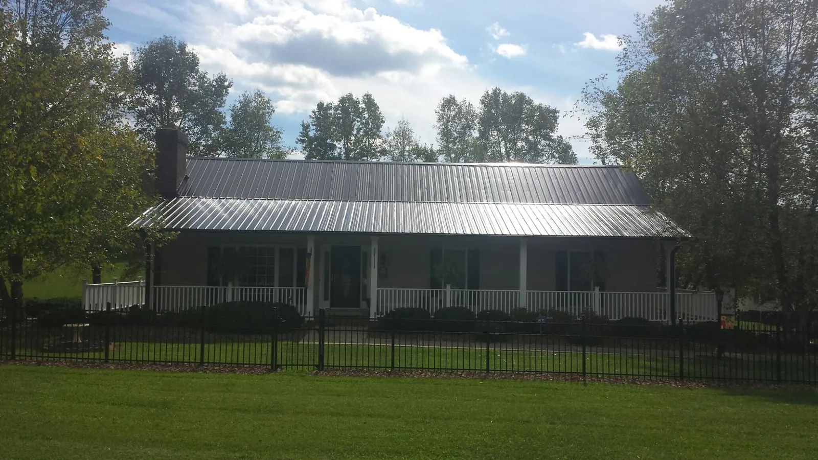 Gray metal roof on a brick ranch with a full width front porch — Gutter Guard Installation work by our crew in Veneta
