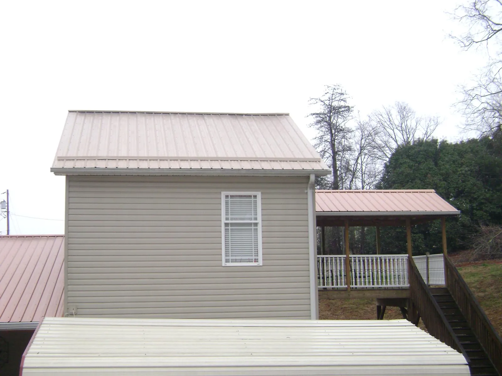 Tan metal roofs on a two story addition and attached porch, from a Roof Replacement job in Veneta