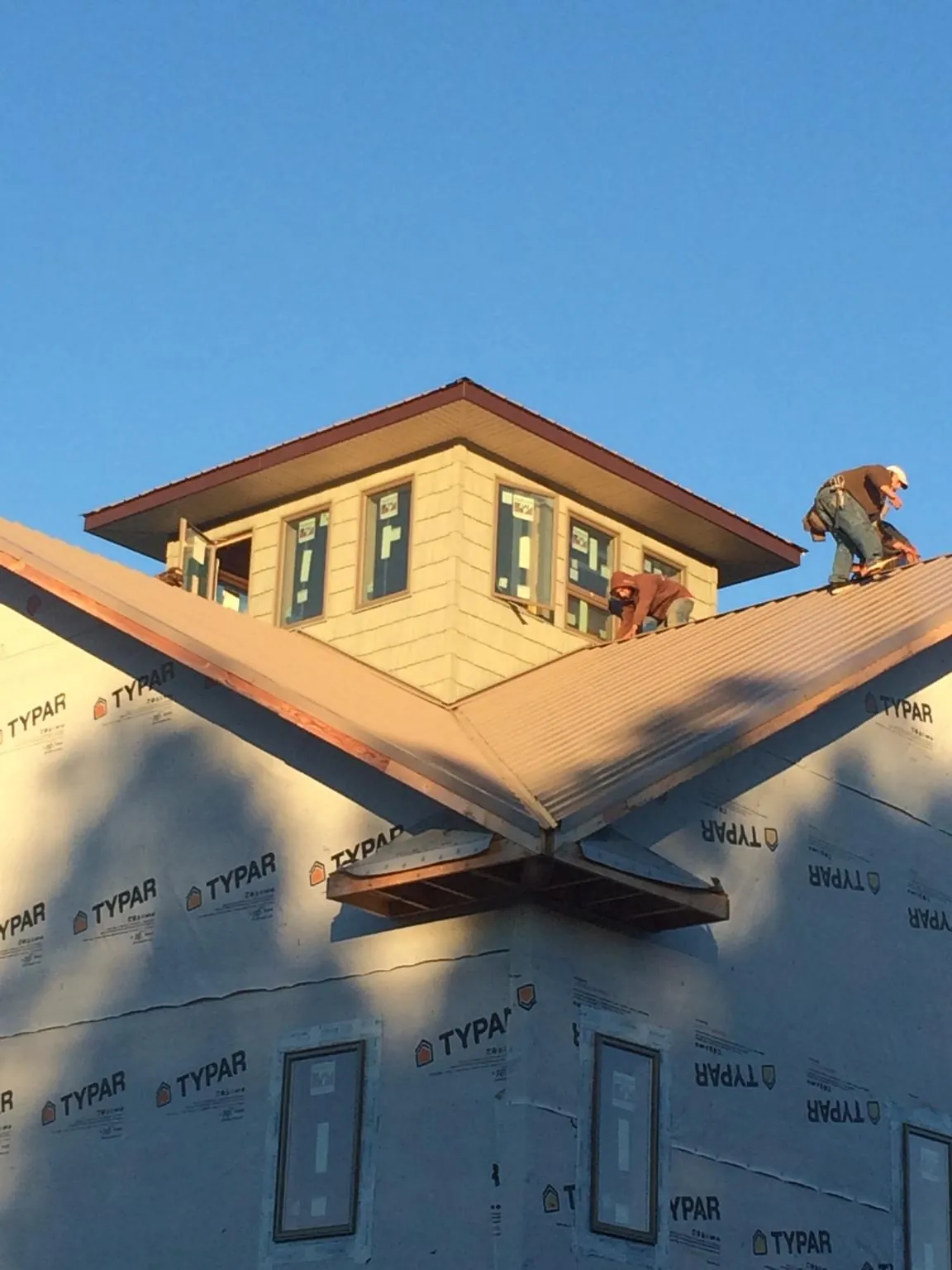 Roofers working around a rooftop cupola on a new metal roof at sunset — Roof Waterproofing in Veneta by Roofing Brothers